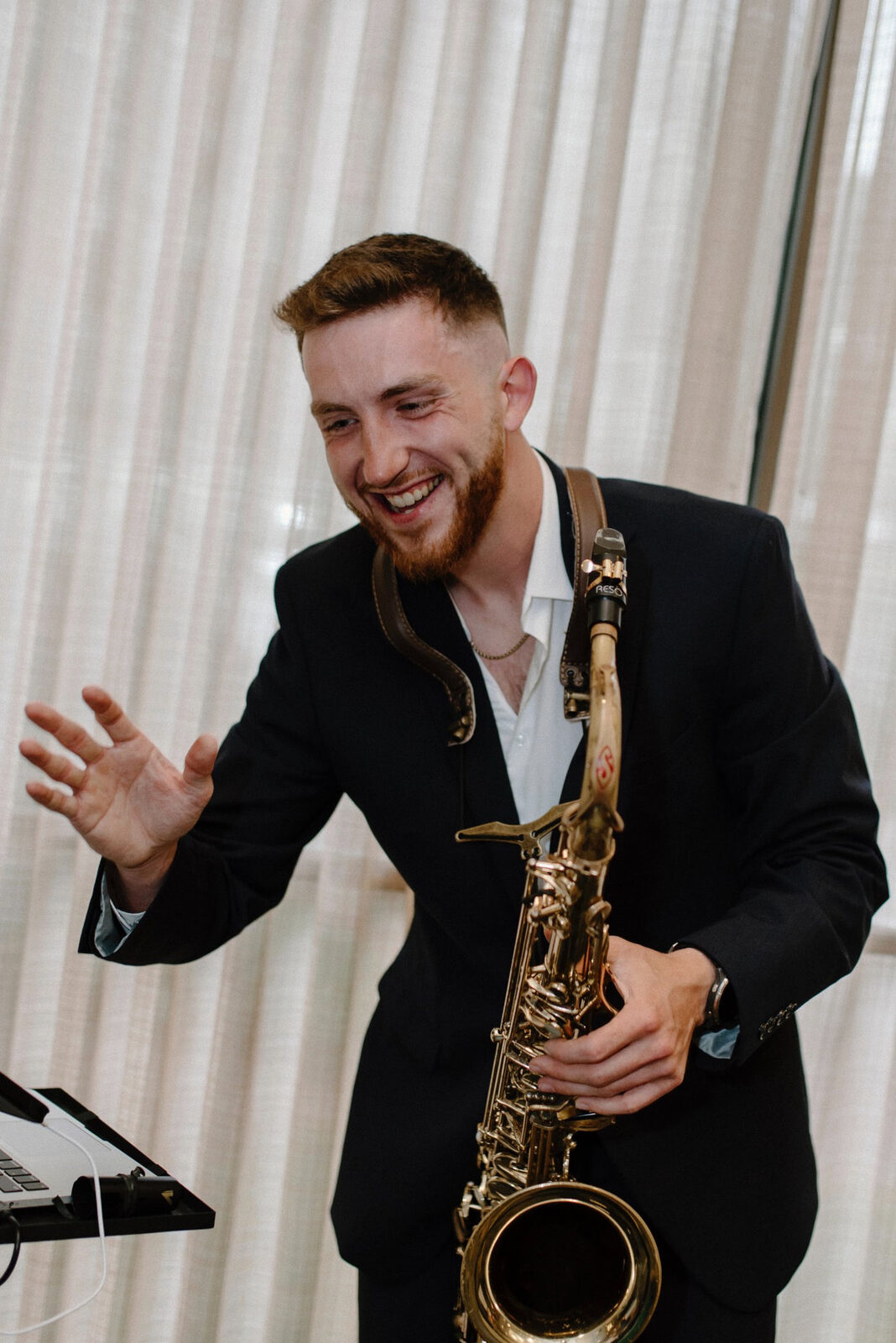 Dawson Bertrand laughing with alto saxophone during a Sax+DJ set at a private event