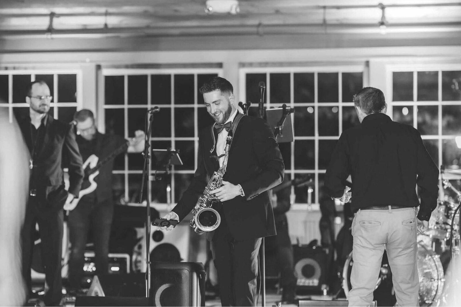 Dawson Bertrand on stage with a full band at a wedding reception, black and white