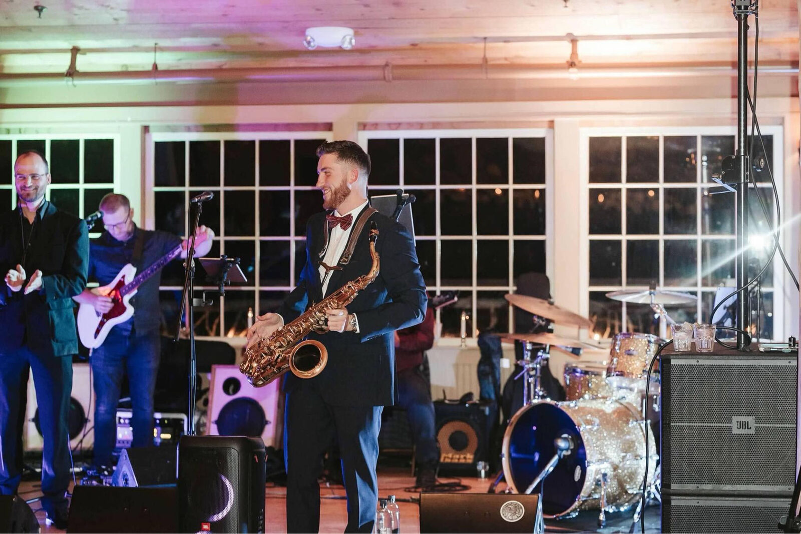 Dawson Bertrand performing with a live band under colorful stage lighting at a wedding