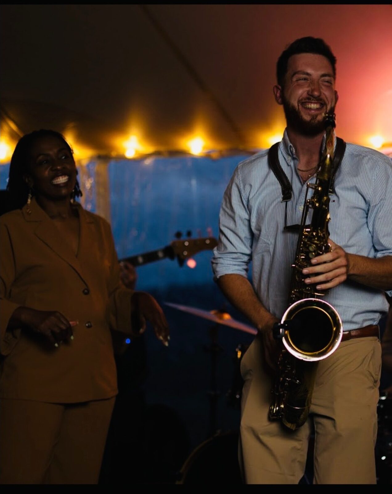 Dawson Bertrand smiling on stage with vocalist during a live band performance